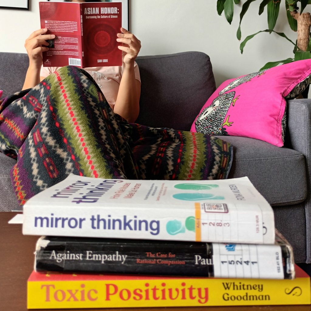 Blogger reading Asian Honor with other self-help books on table